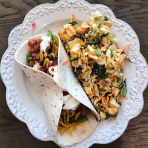 Loaded pork carnitas taco with tomato salsa, cheese, green pepper, onions, avocado, and sour cream with a chipotle south west salad on the side as one of the easy dinners in the easiest Aldi meal plan, which delivers 14 dinners to your front door for under $150.