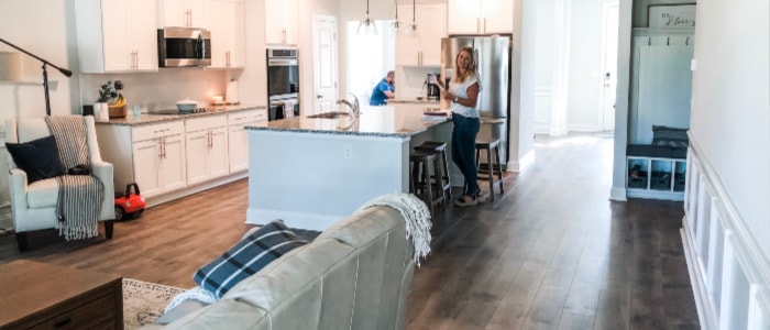 A clean and organized house after implementing home management routines. Mom sorting bills on the kitchen table, dad working in the dining room. 