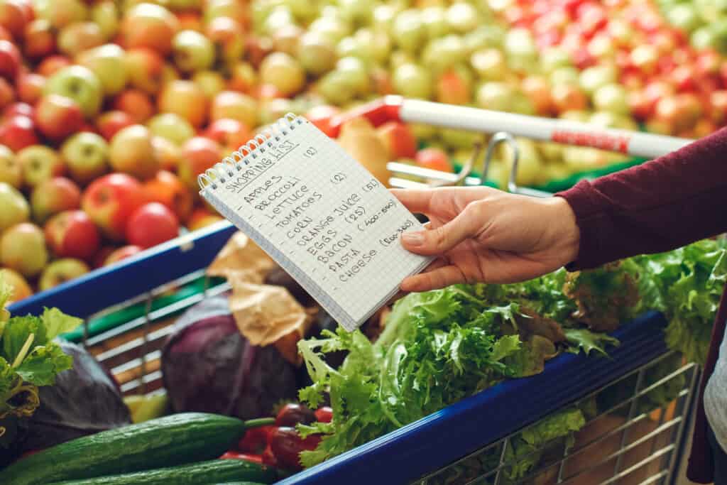 Woman shopping at the grocery store with a list.