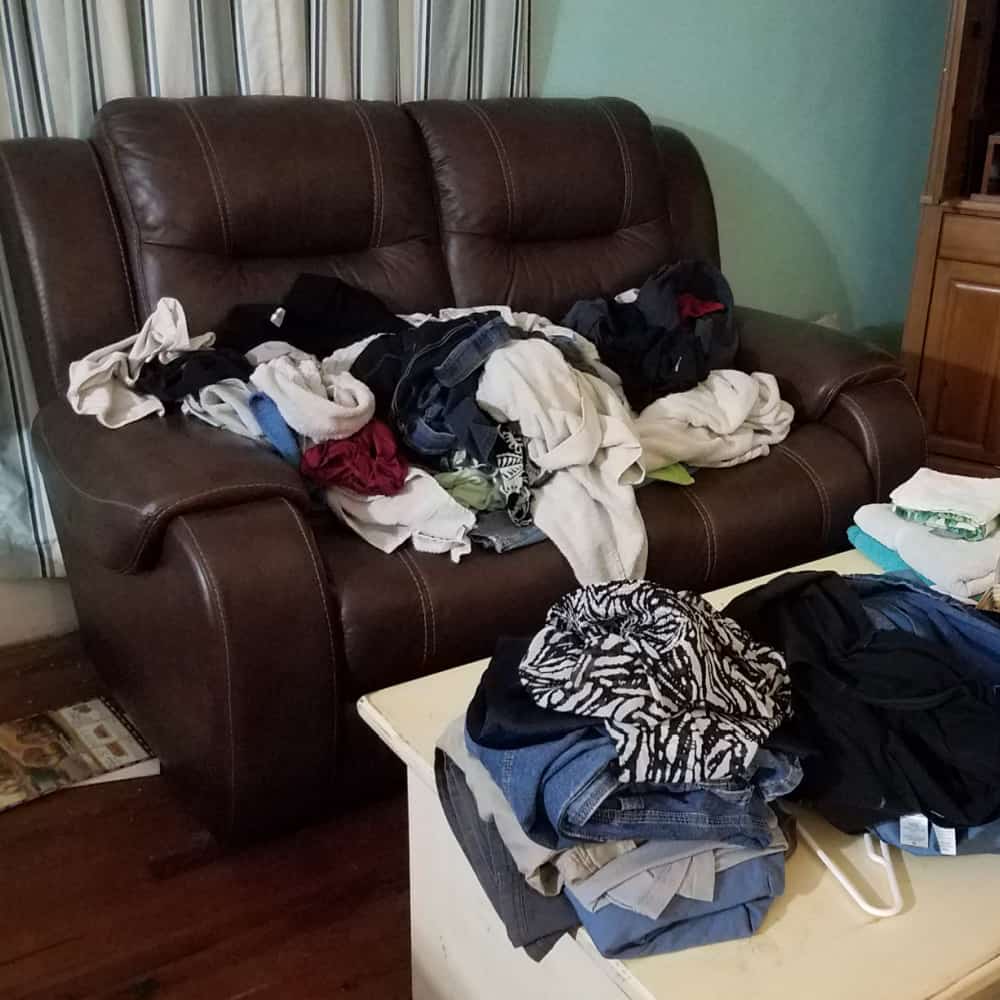 Messy House displaying a messy living room or coffee table with clothing, trash, and hangers in this trashed house. 