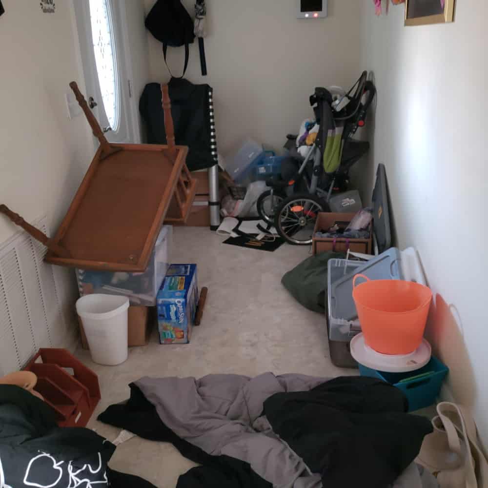 Messy House displaying a messy hallway or door entry with clothing, trash, organizing containers and broken furniture in this trashed house. 