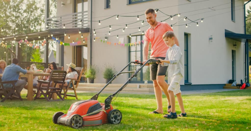 Father teaching son to mow the lawn.