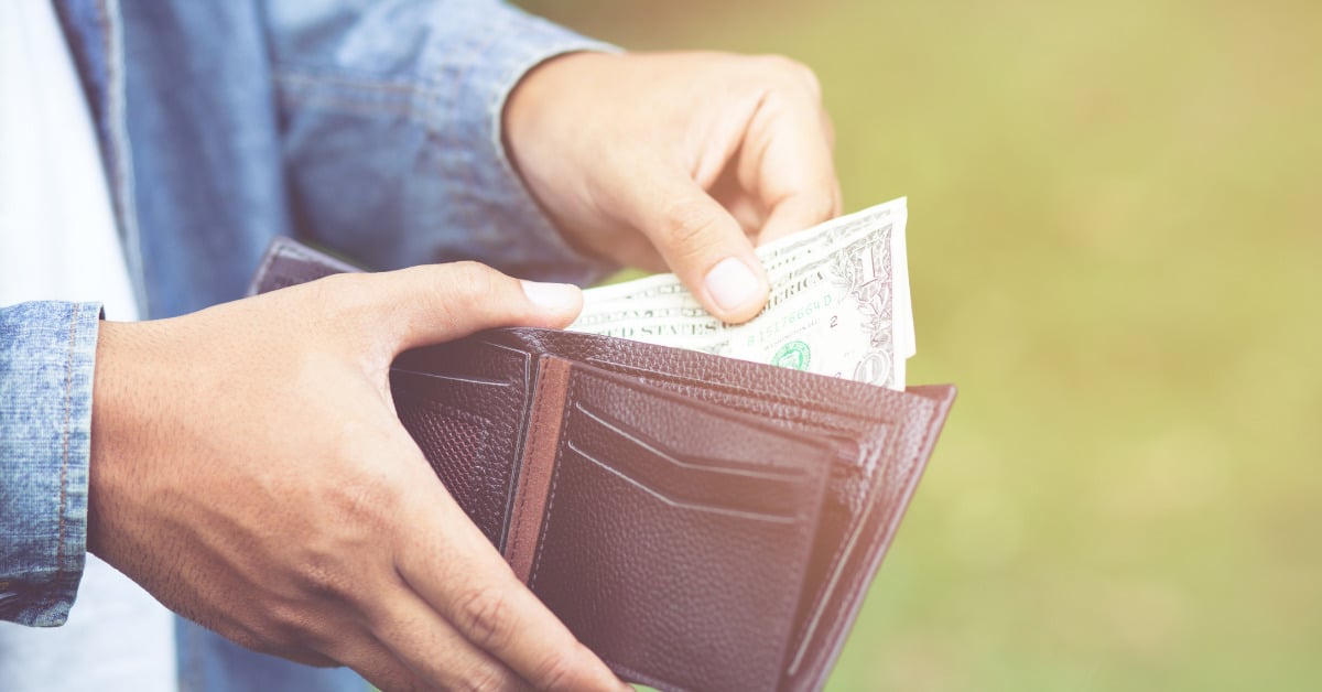 woman sifting through money in her wallet.