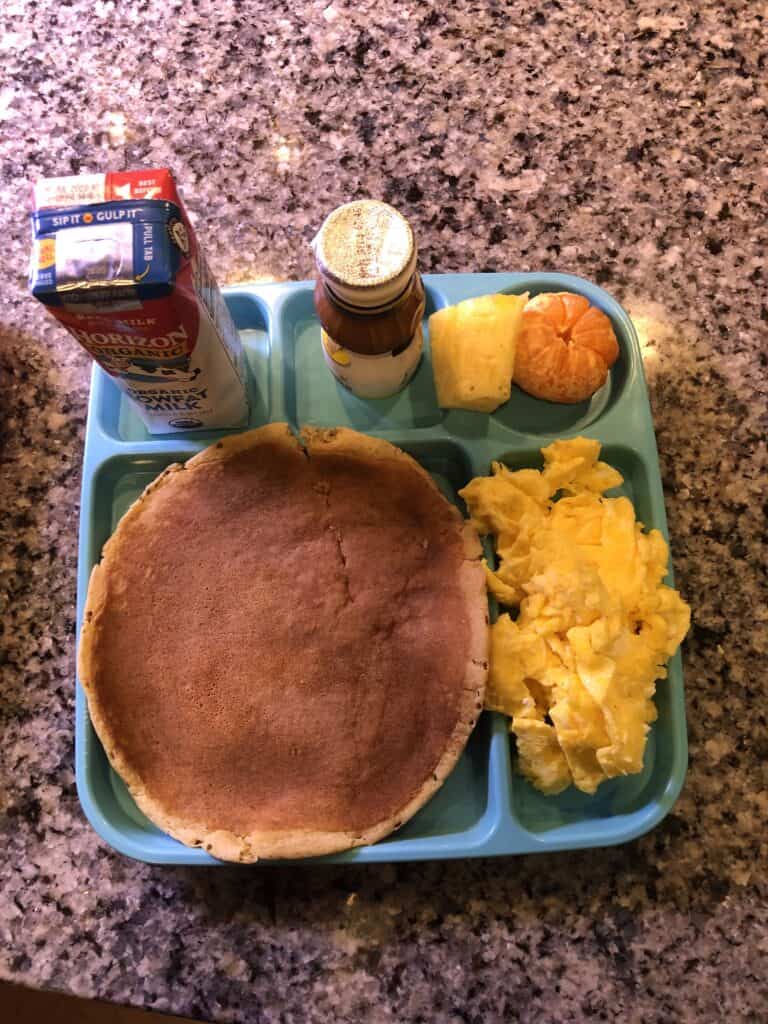 Pancakes and eggs fruit and a milk container.