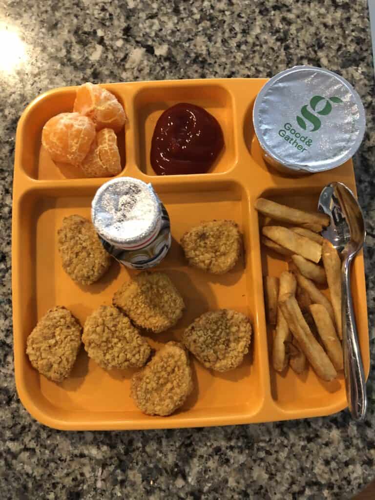 Chicken nuggets, fruit, fries and applesauce on a tray.