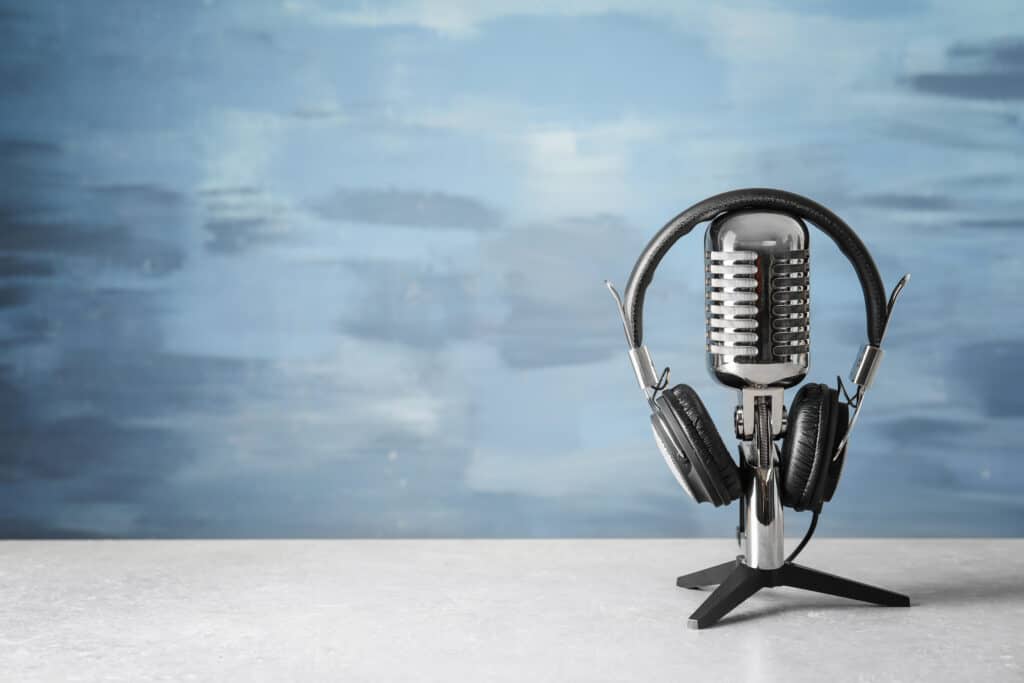 Retro microphone and headphones on table against blue wall