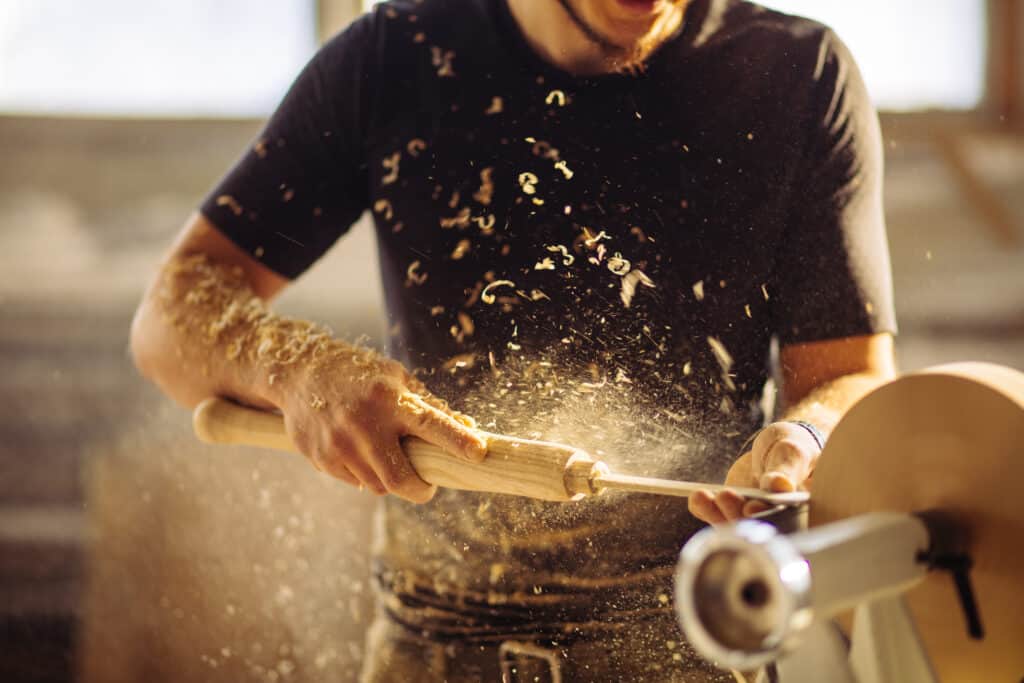 Turner working on a lathe in the workshop. Male hand carving wooden peice.